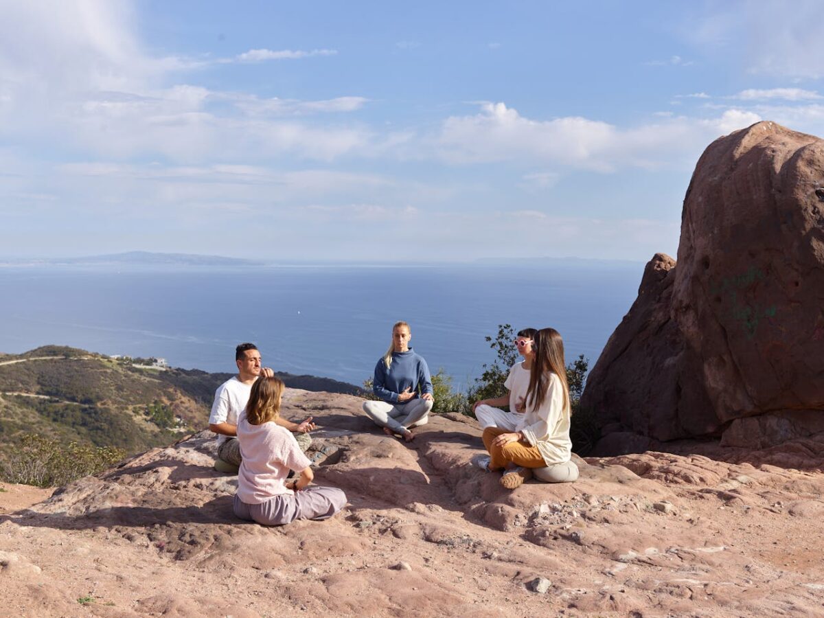 A group of people meditating on a cliff with stunning ocean views, promoting serenity and mindfulness.