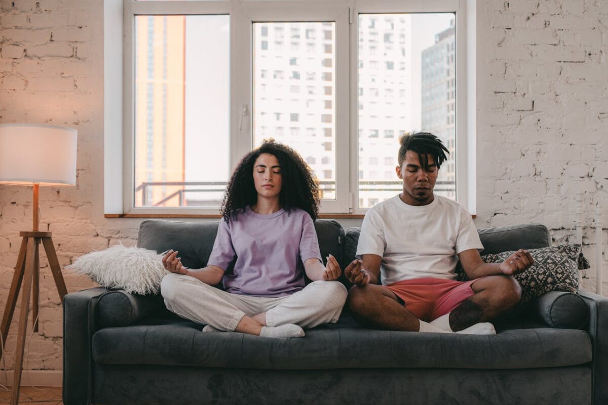 Relaxing meditation in a bright living room setting with a couple practicing mindfulness.